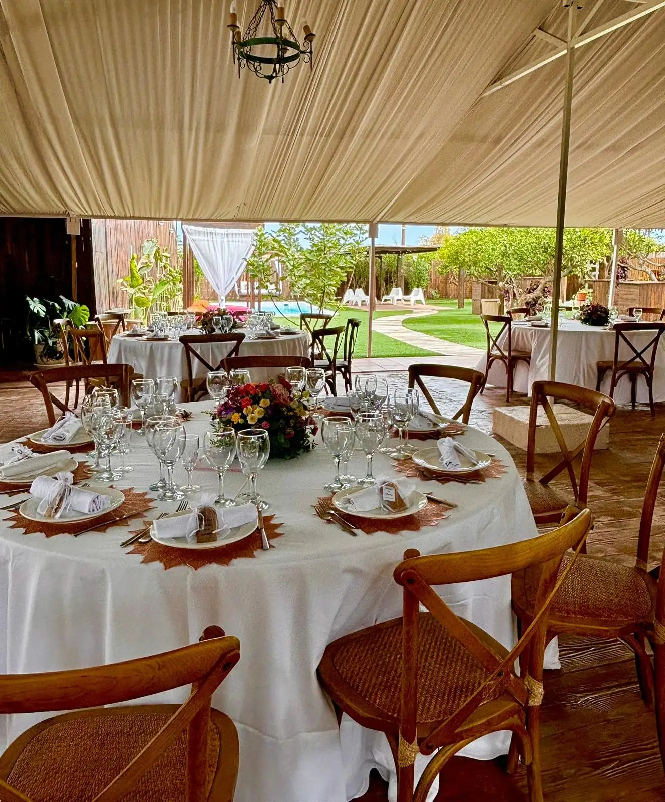 El interior de la carpa con las mesas redondas puestas y, al fondo, el jardín visto a través de la entrada